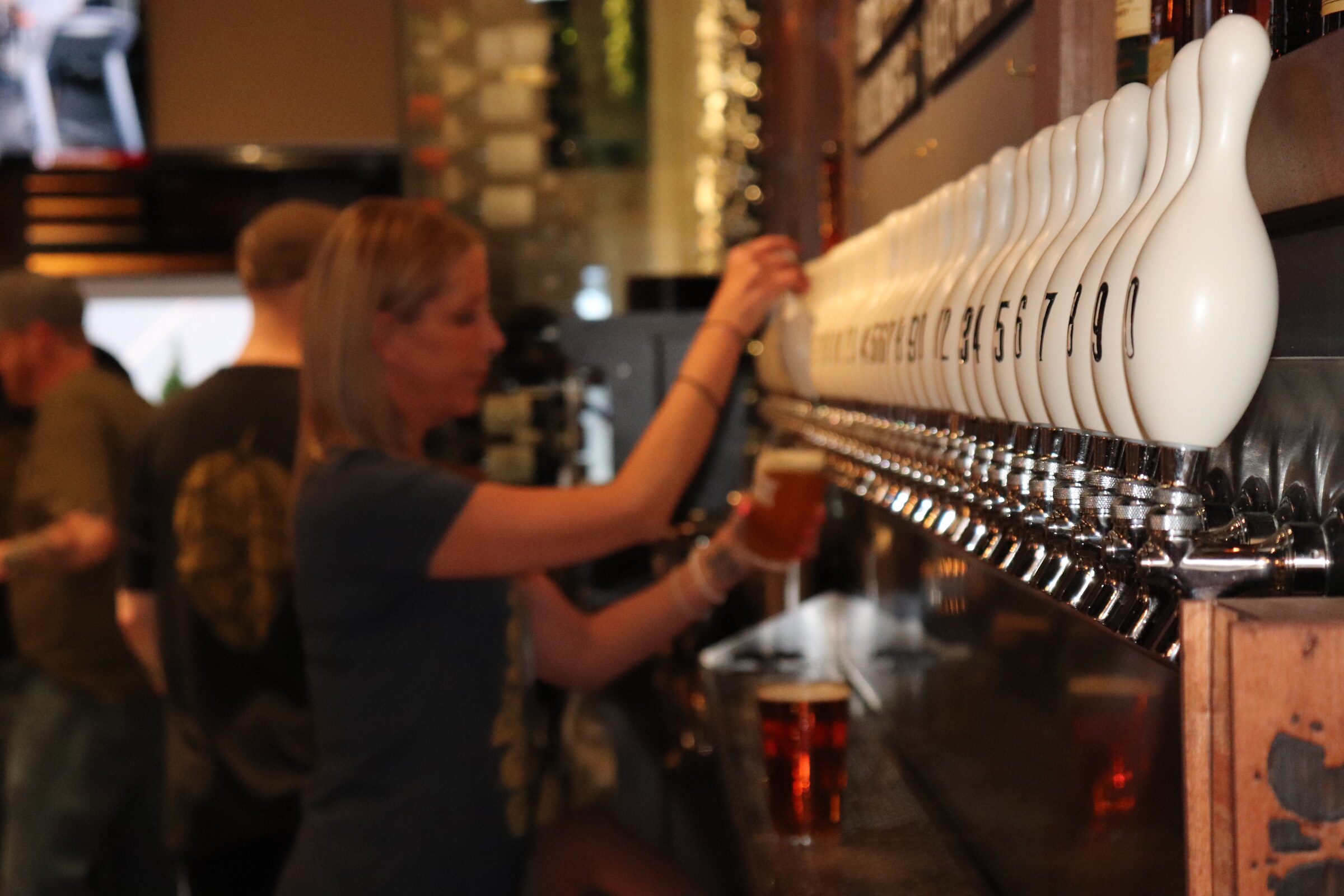 Bartender pouring a craft beer from the tap wall at Hoppin’ Vines